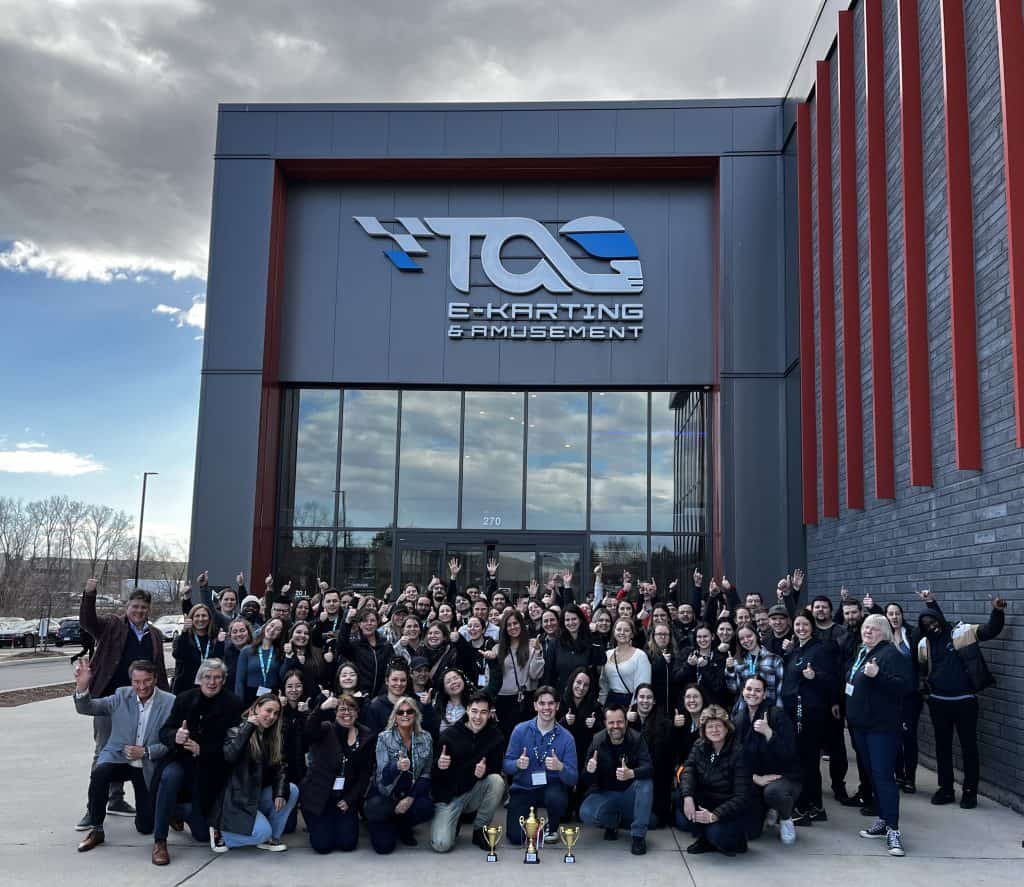 Vibrant group of participants at a karting and amusement event, in front of the TGC E-Karting & Amusement center, a friendly corporate gathering.