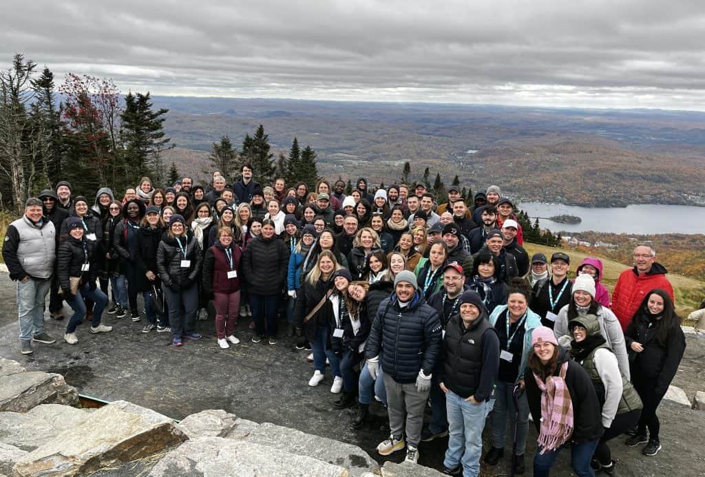 A group of people on an autumn excursion with a panoramic view of a lake and mountains, dressed in warm clothing.