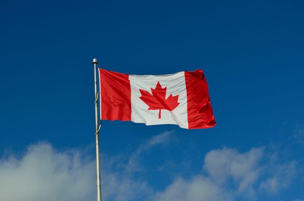 Drapeau canadien flottant dans le ciel bleu, symbolisant le budget fédéral 2025 et les annonces en taxes au Canada.