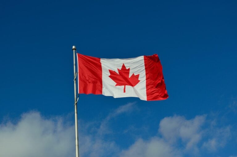Canadian flag flying in the blue sky, symbolizing the 2025 federal budget and tax announcements in Canada.